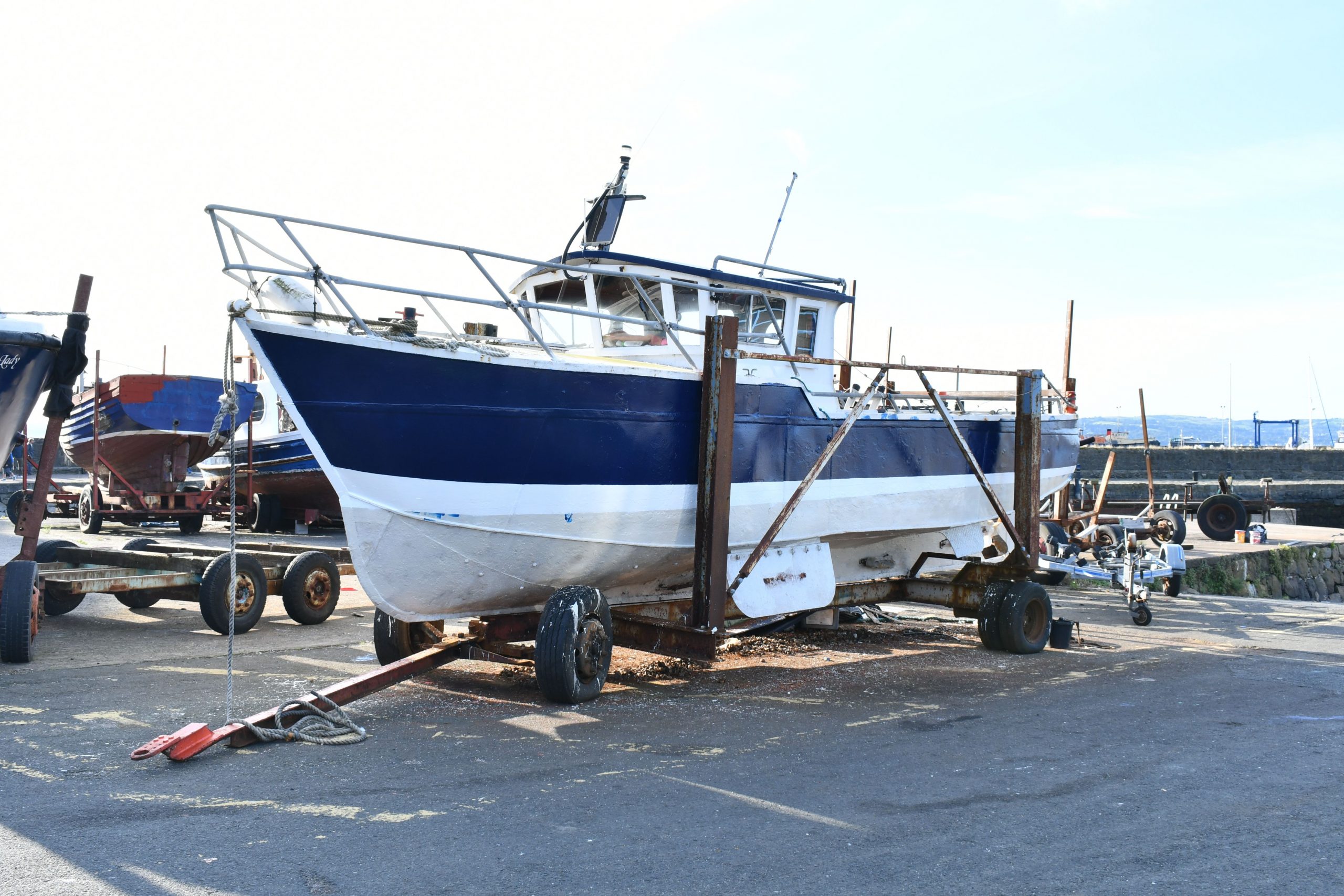 A small fishing boat out of the water awaiting repairs